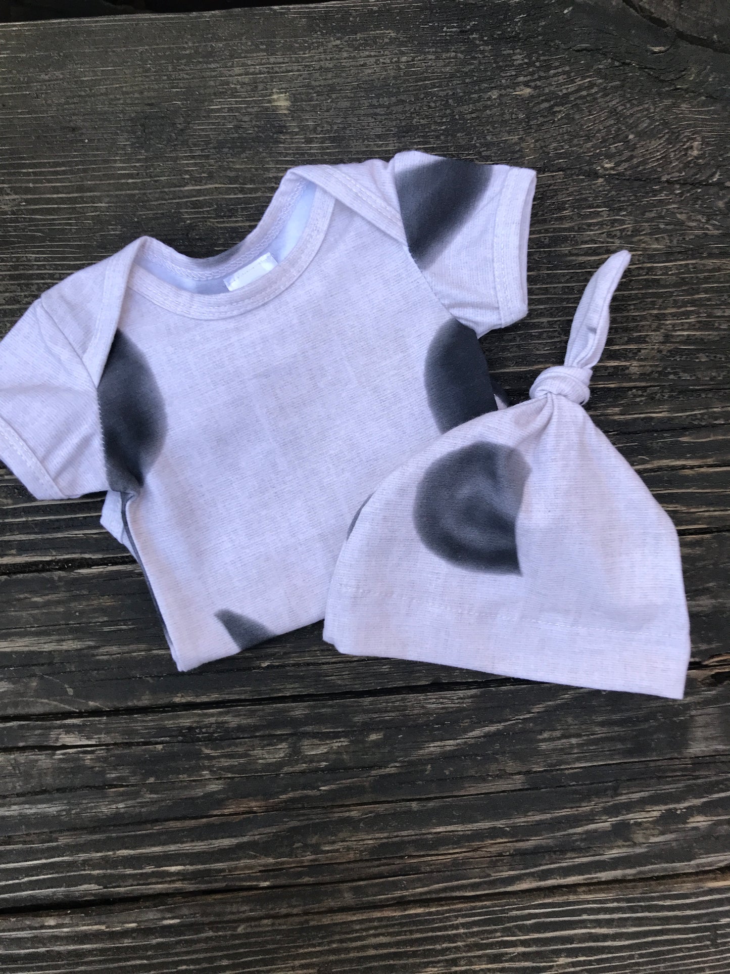 Short sleeve moon phase onesie with hat on a wood bench