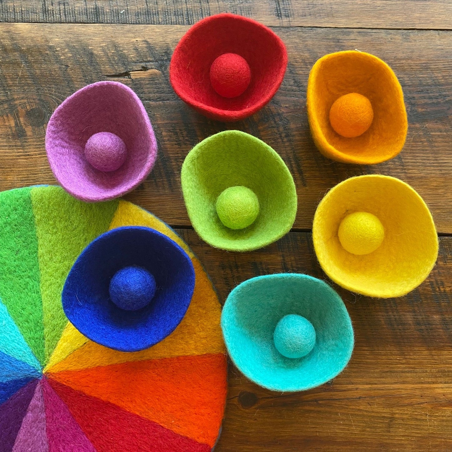 Colorful felt bowls with balls on a wooden surface