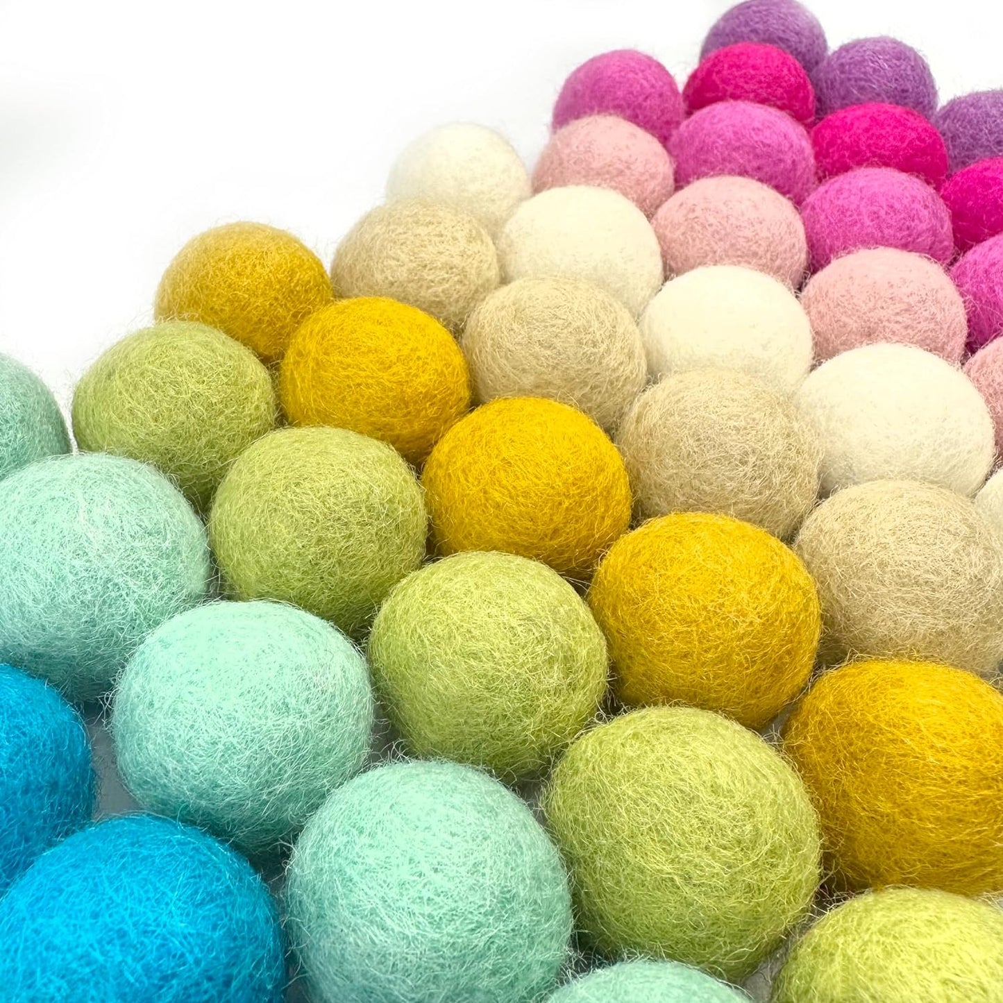 Colorful felt balls arranged in a pattern on a white background