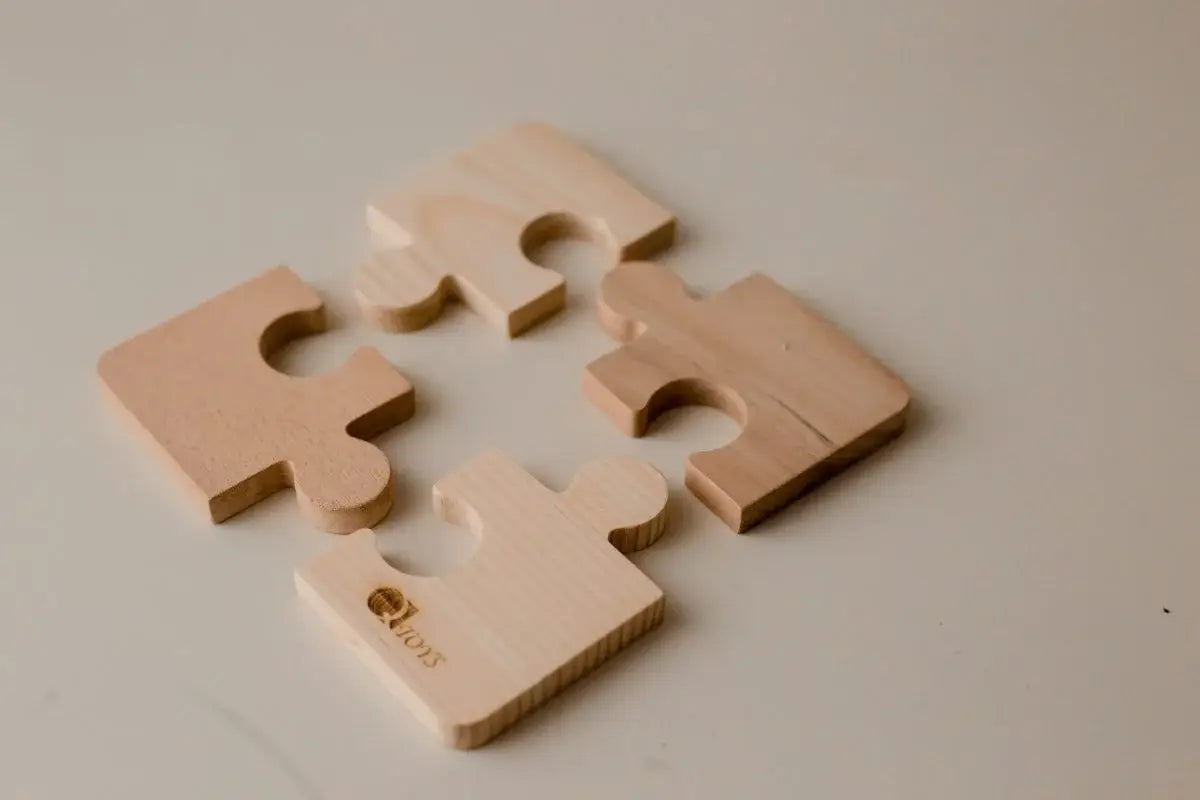 Four wooden puzzle pieces on a light gray background