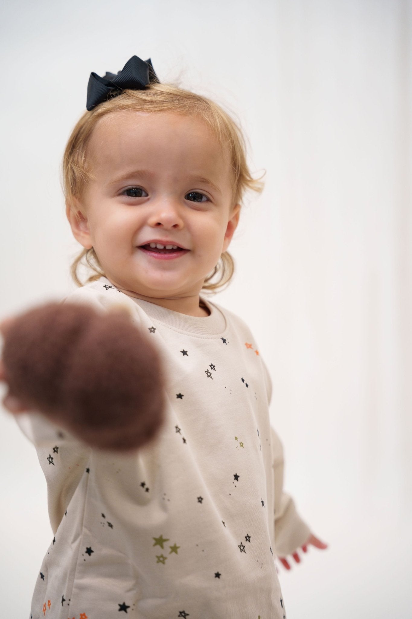 Child wearing a white shirt with star patterns on a plain background