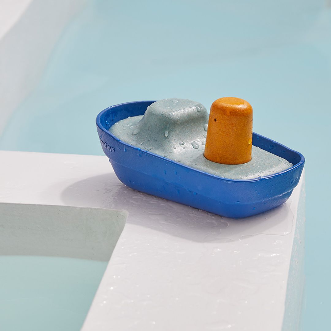 Toy boat with a mountain and orange buoy on a white surface