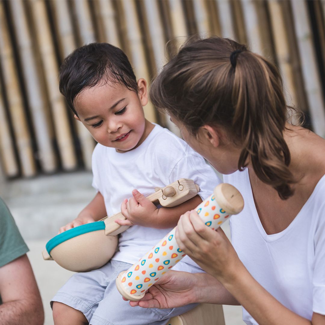 Woman and child playing with wooden toys outdoors