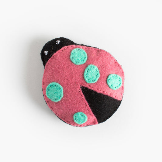 Pink ladybug-shaped toy with green spots on a white background