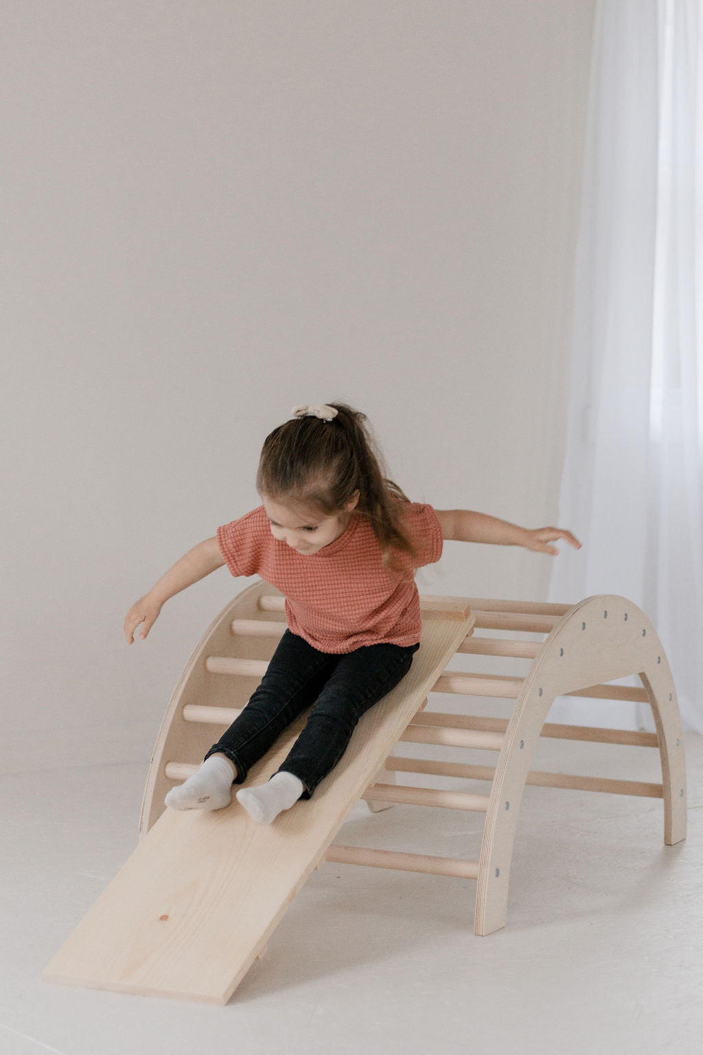 Child playing on a wooden climbing toy indoors