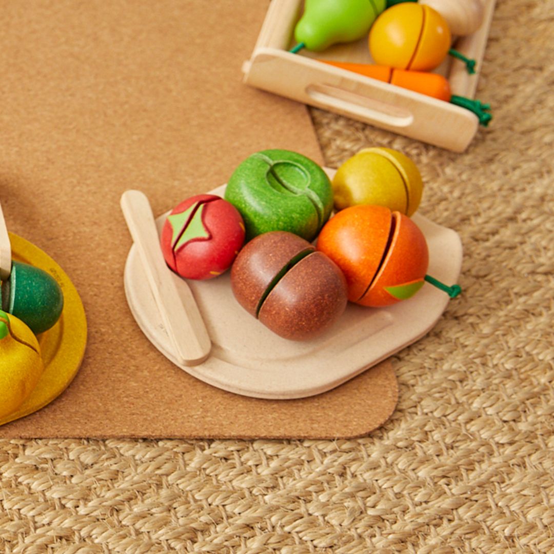 Colorful wooden toy fruits and vegetables on a brown mat