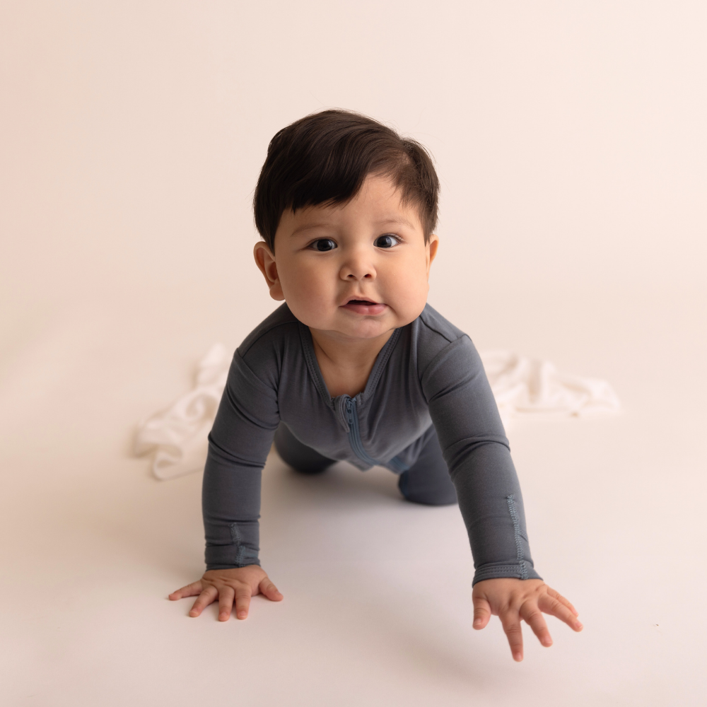 Baby in a gray outfit crawling on a light-colored floor.