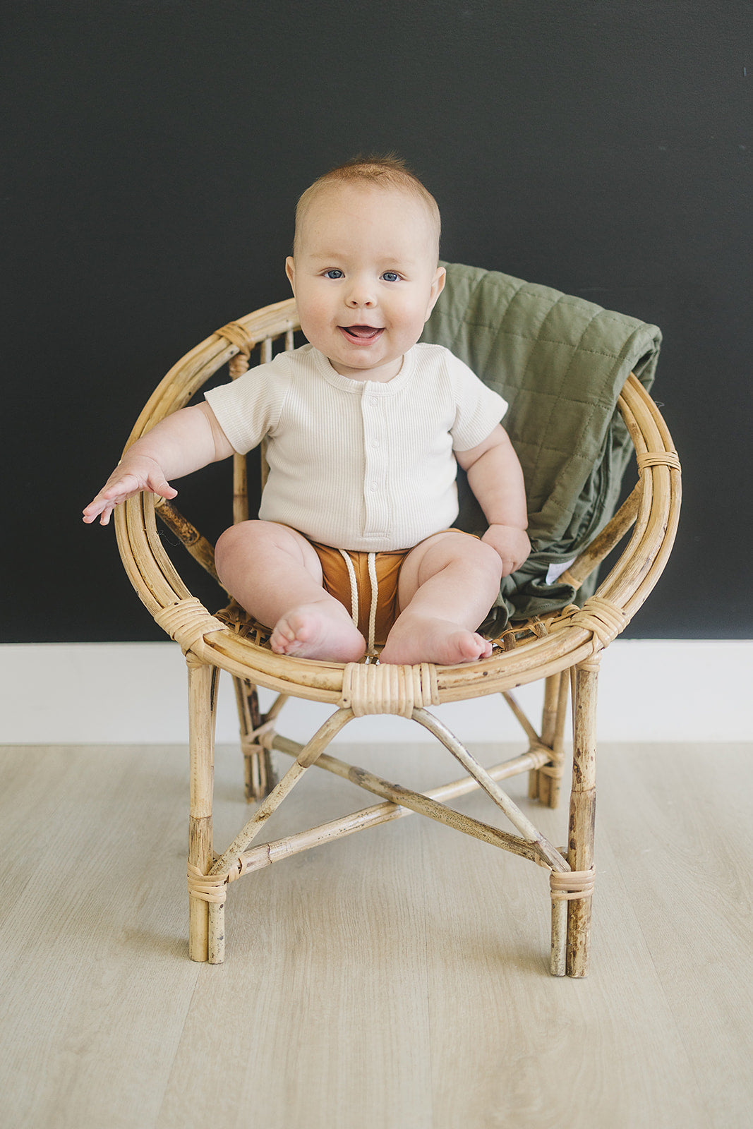 Baby sitting in a wicker chair with a dark background