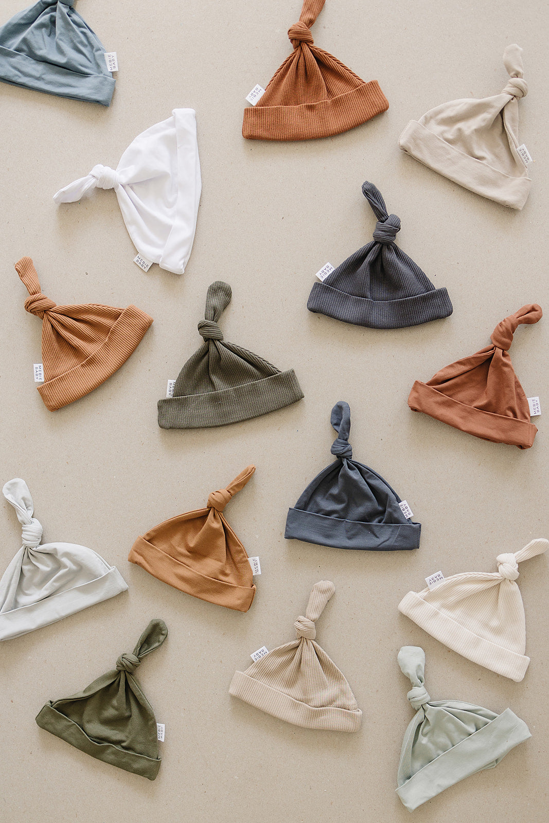 Collection of baby hats in various colors on a beige background
