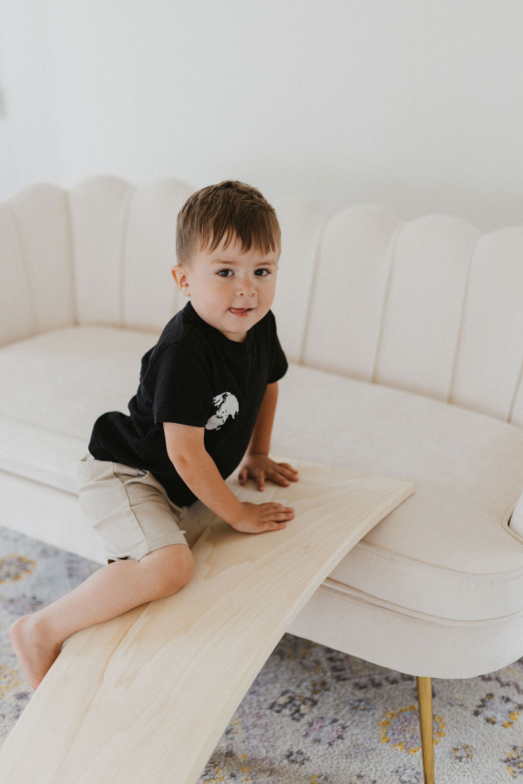 Child sitting on a white couch with a wooden board