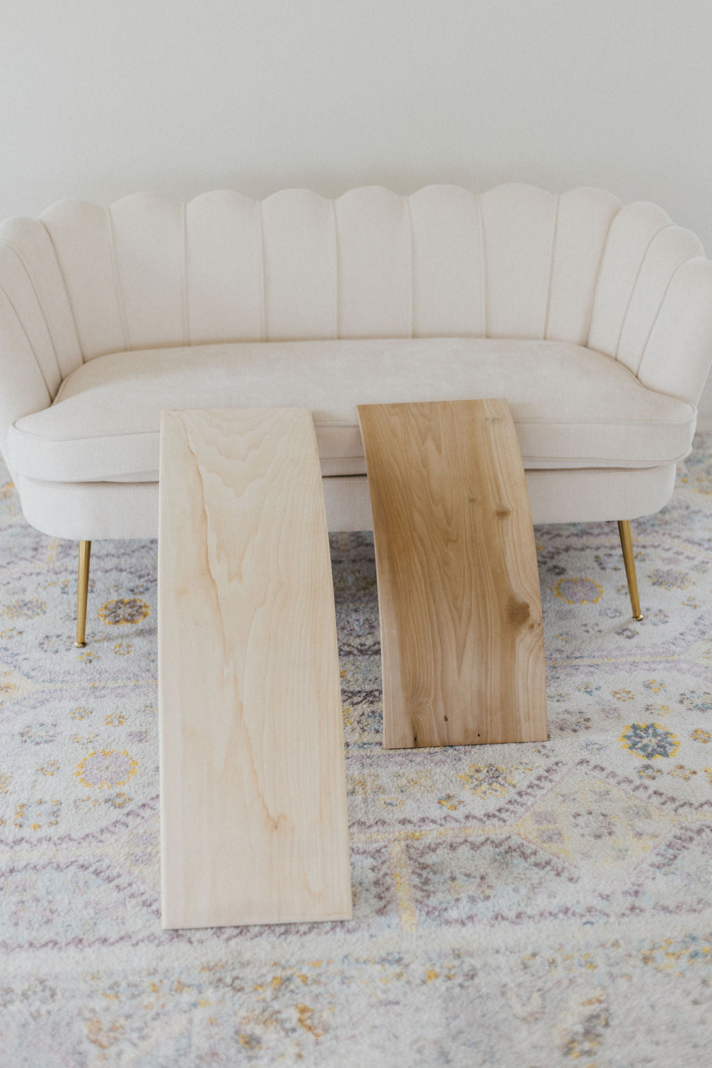 Two wooden tables in front of a white sofa on a patterned rug.