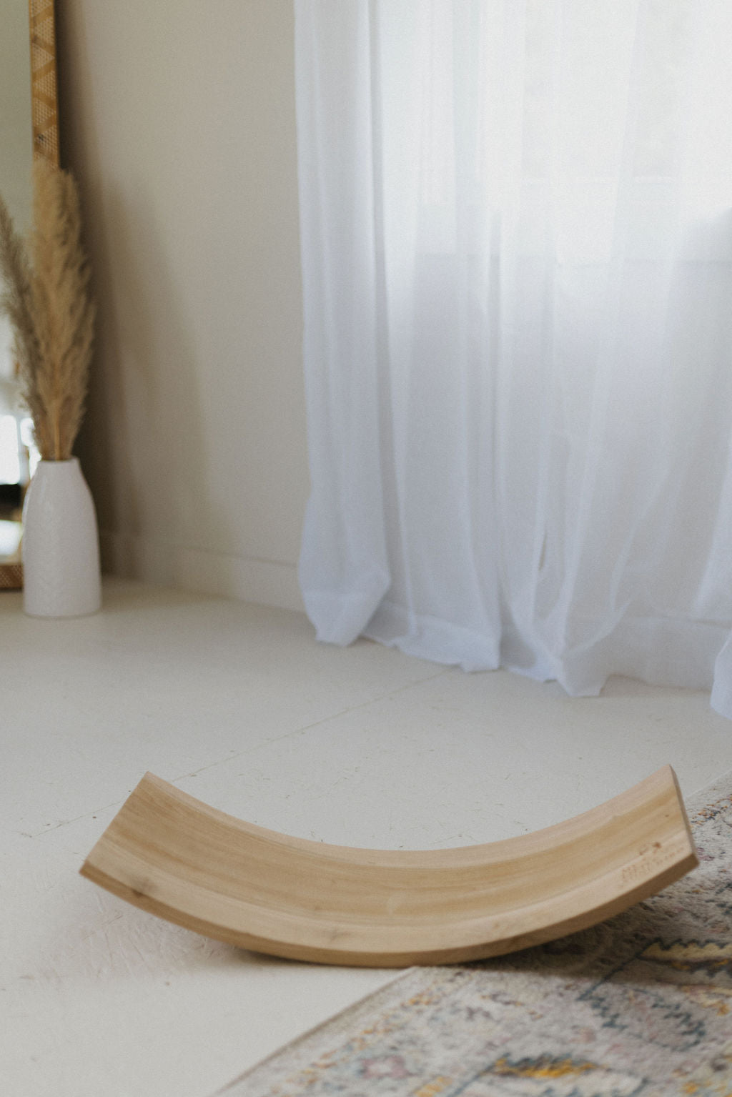 Wooden cat shelf on a light-colored floor with a white curtain in the background