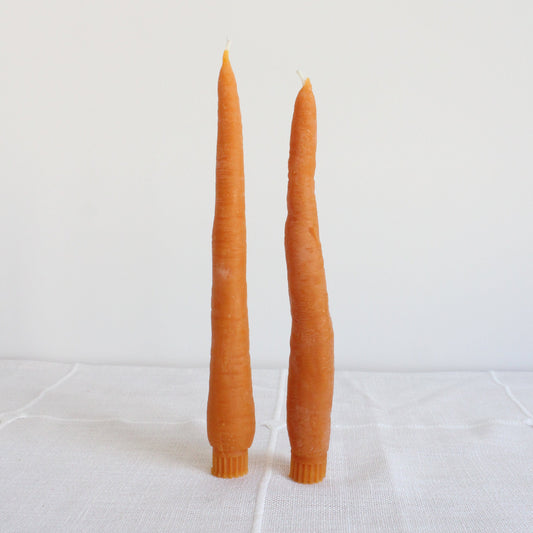 Two carrot-shaped candles on a white background