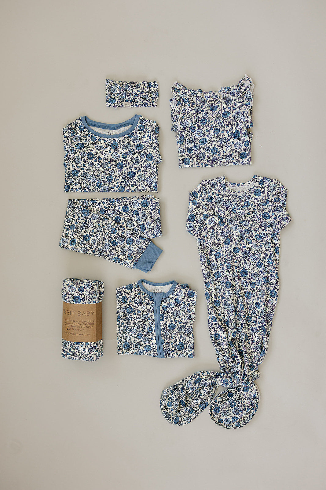 Collection of baby clothing items with blue floral pattern on a beige background