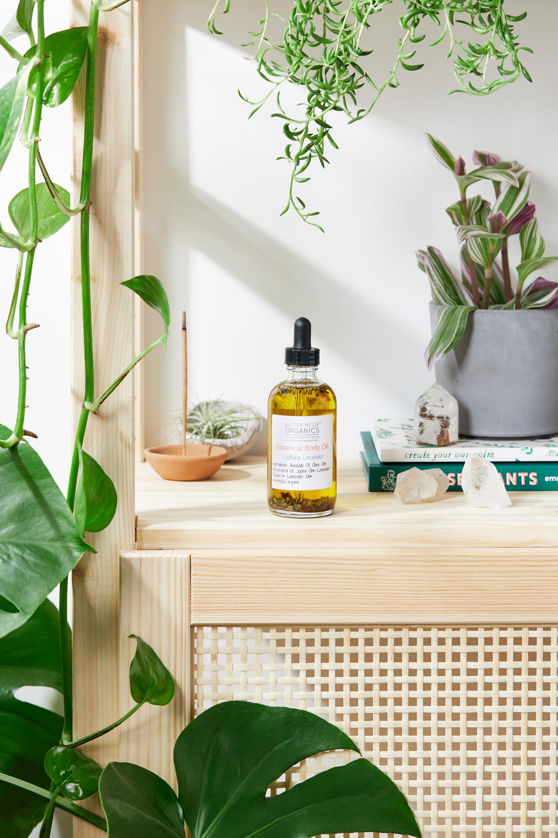 Bottle of oil on a wooden shelf with plants in the background