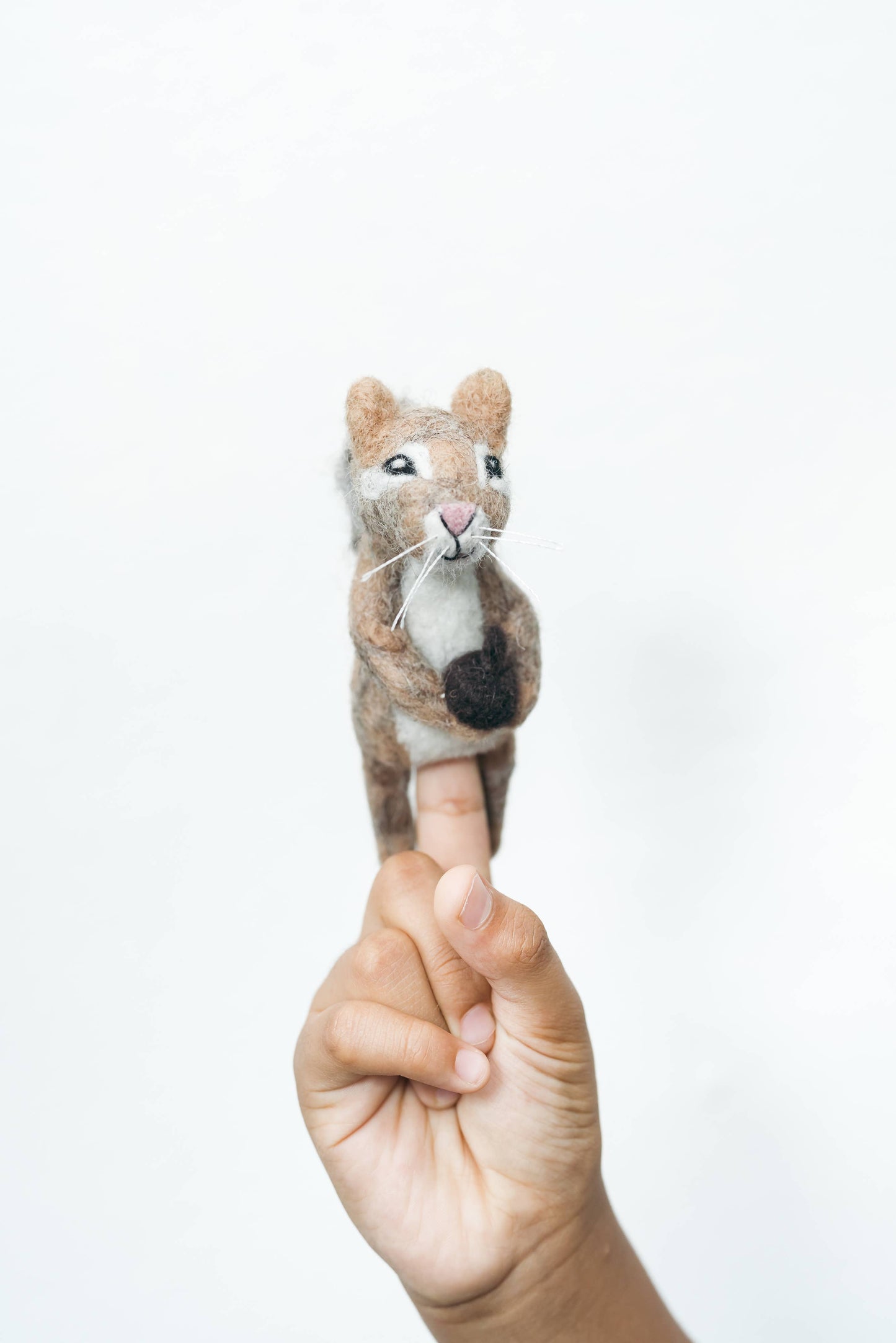 Finger puppet of a chipmunk held on a finger against a white background