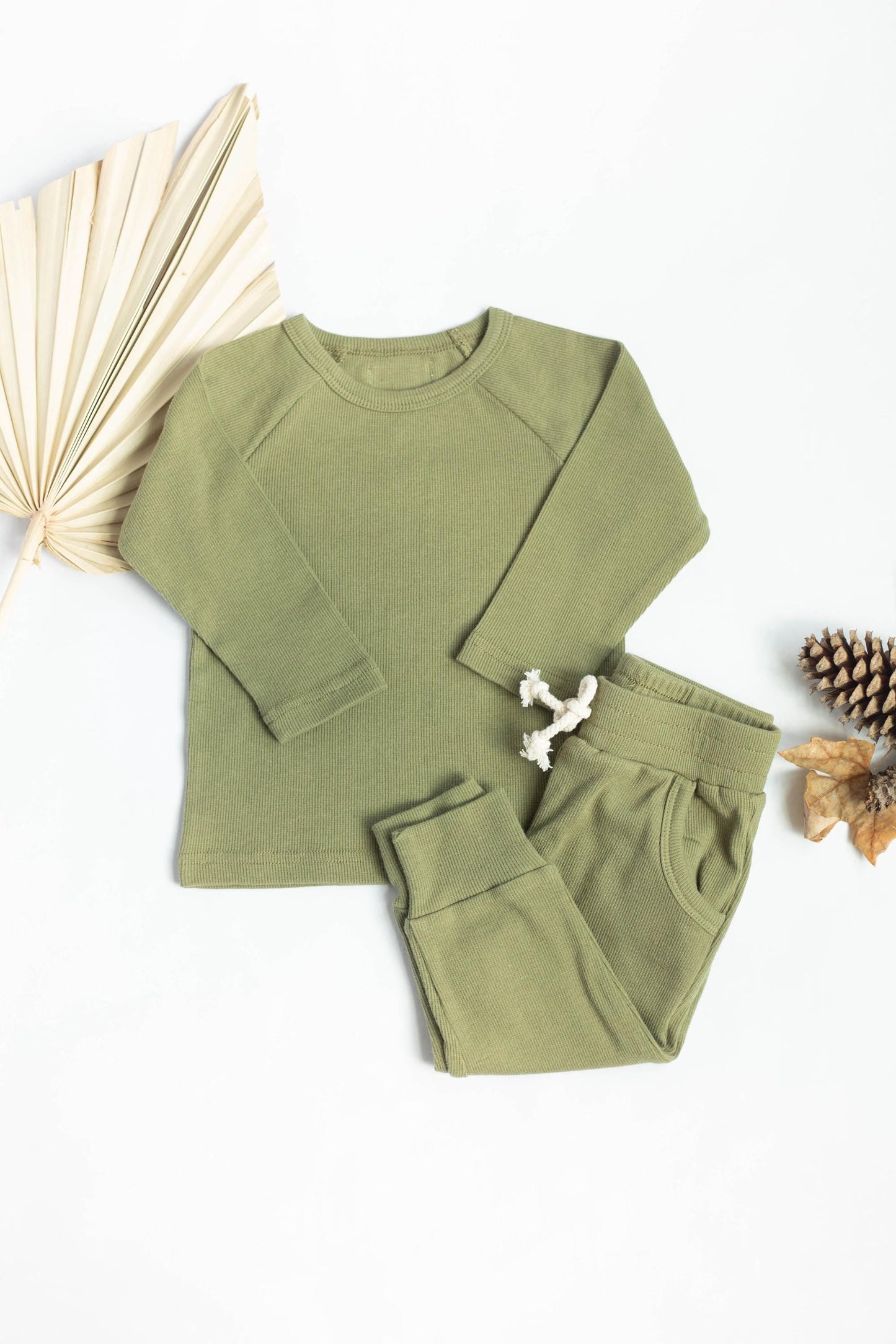 Green children's sweatshirt and pants set with decorative elements on a white background