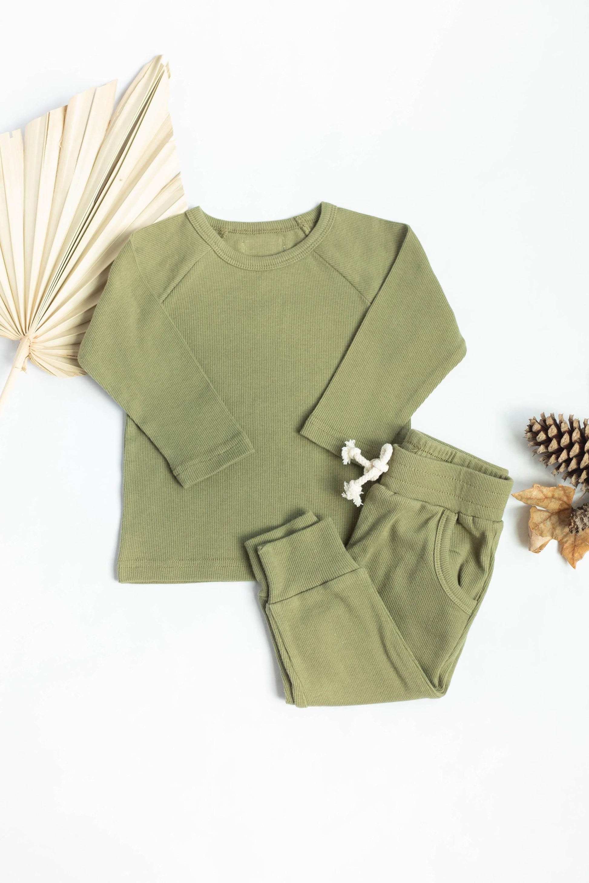 Green children's sweatshirt and pants set with decorative elements on a white background