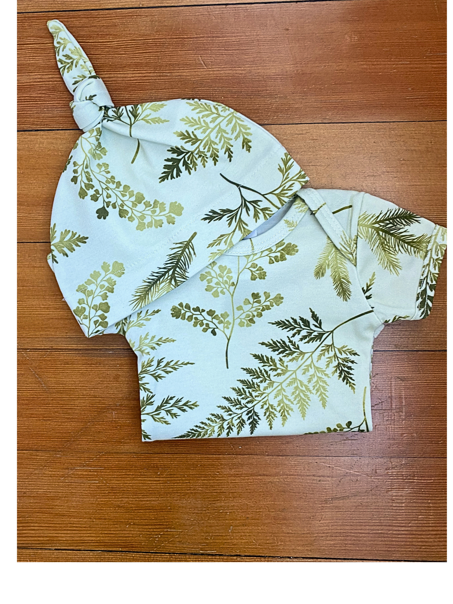 Baby outfit with floral pattern on a wooden surface