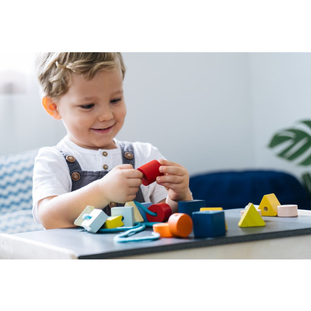 Child playing with colorful building blocks on a table.