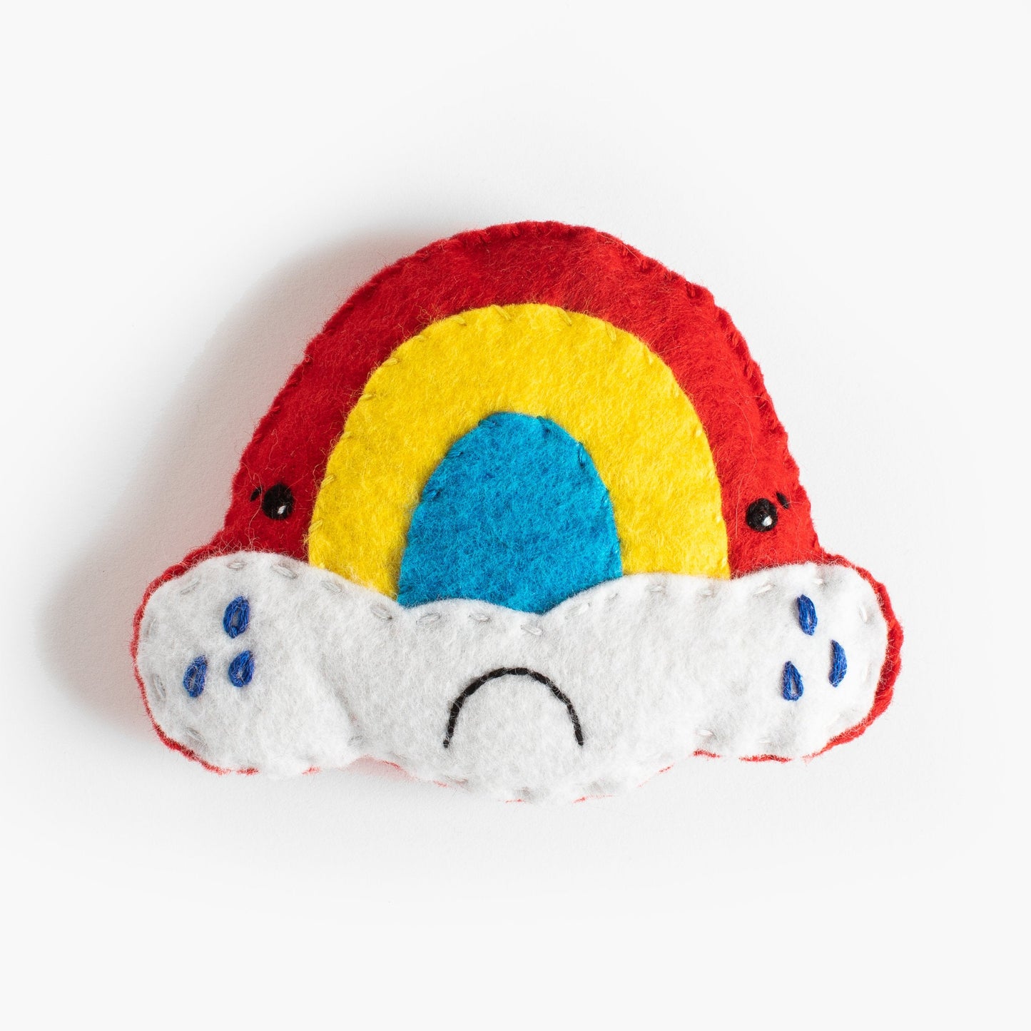 Colorful rainbow-shaped toy with white cloud base on a white background