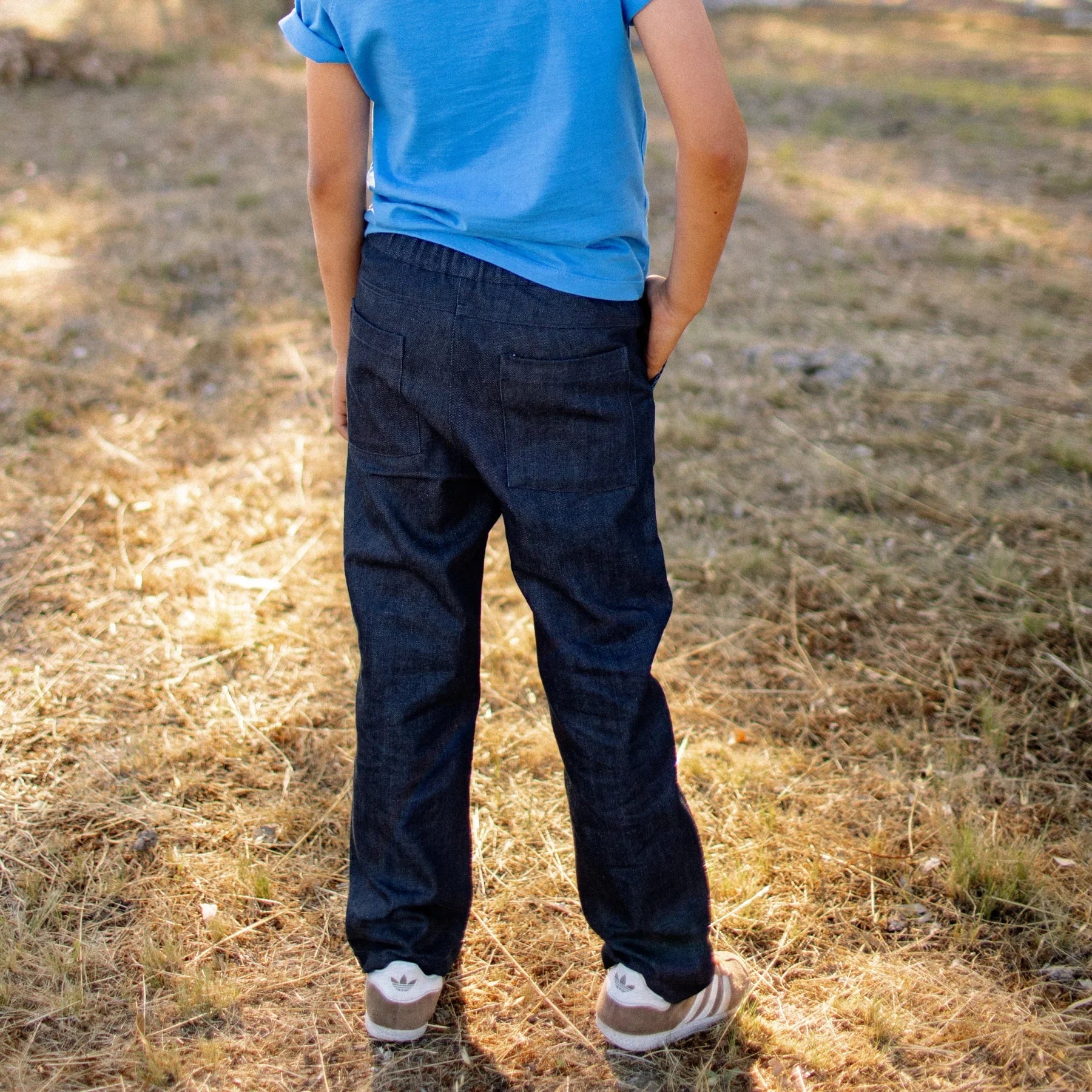 Person wearing a blue shirt and dark pants standing on dry grass