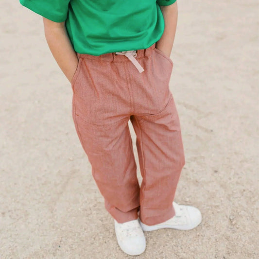 Person wearing a green shirt and pink pants on a beige background