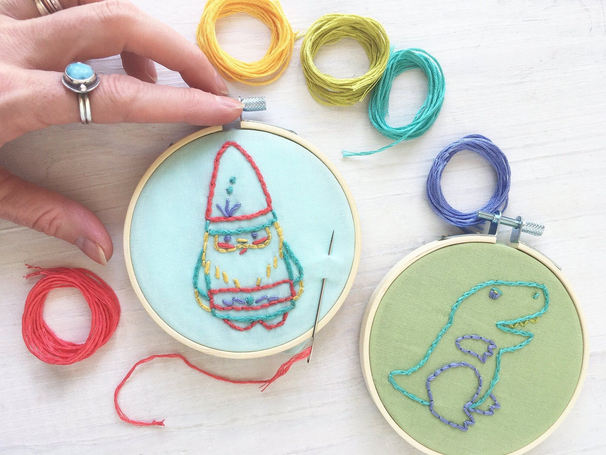 Embroidery hoops with colorful thread and a gnome design on a light surface.