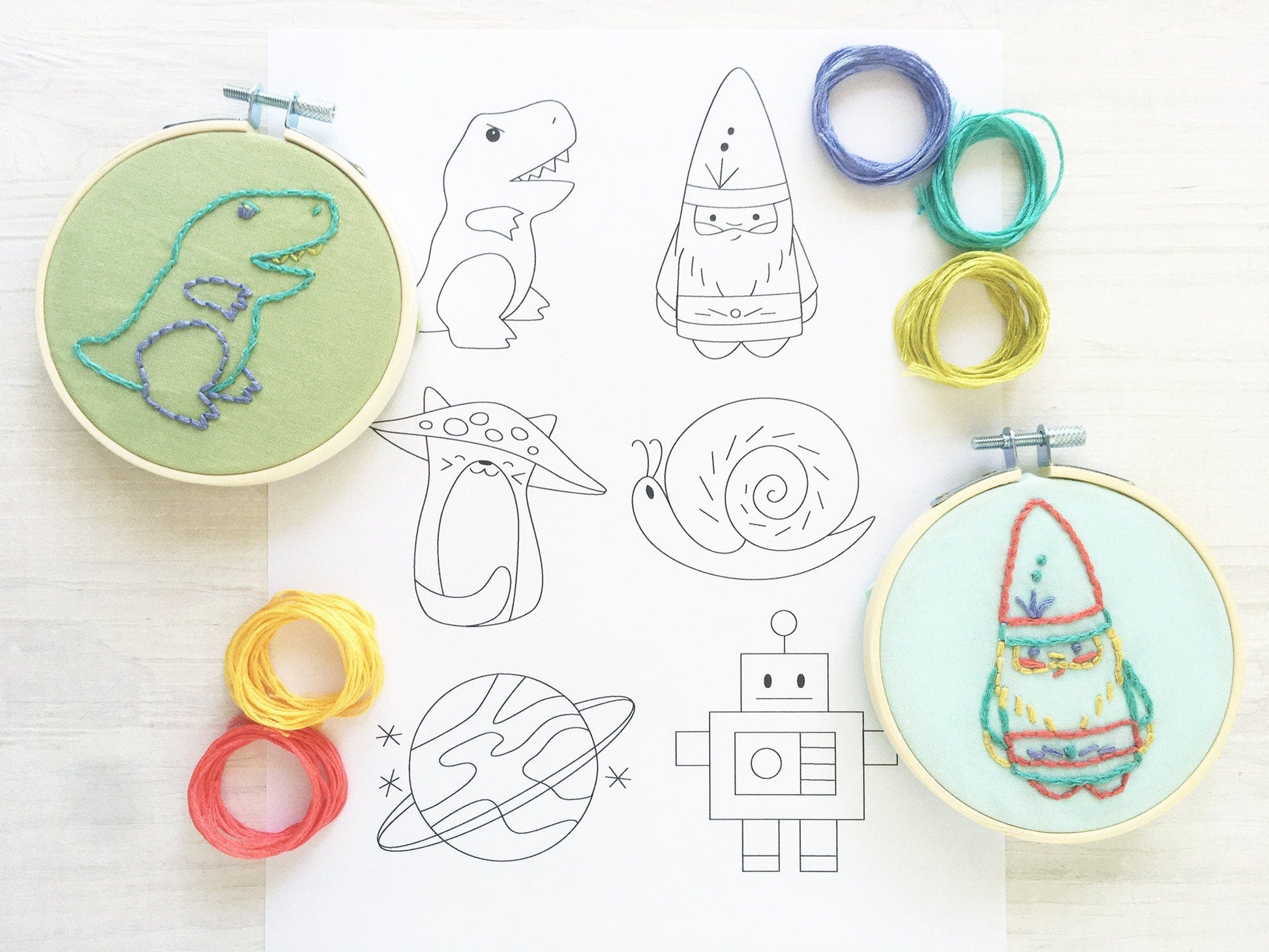 Embroidery hoops with embroidered designs on a white background with templates and colored rings.