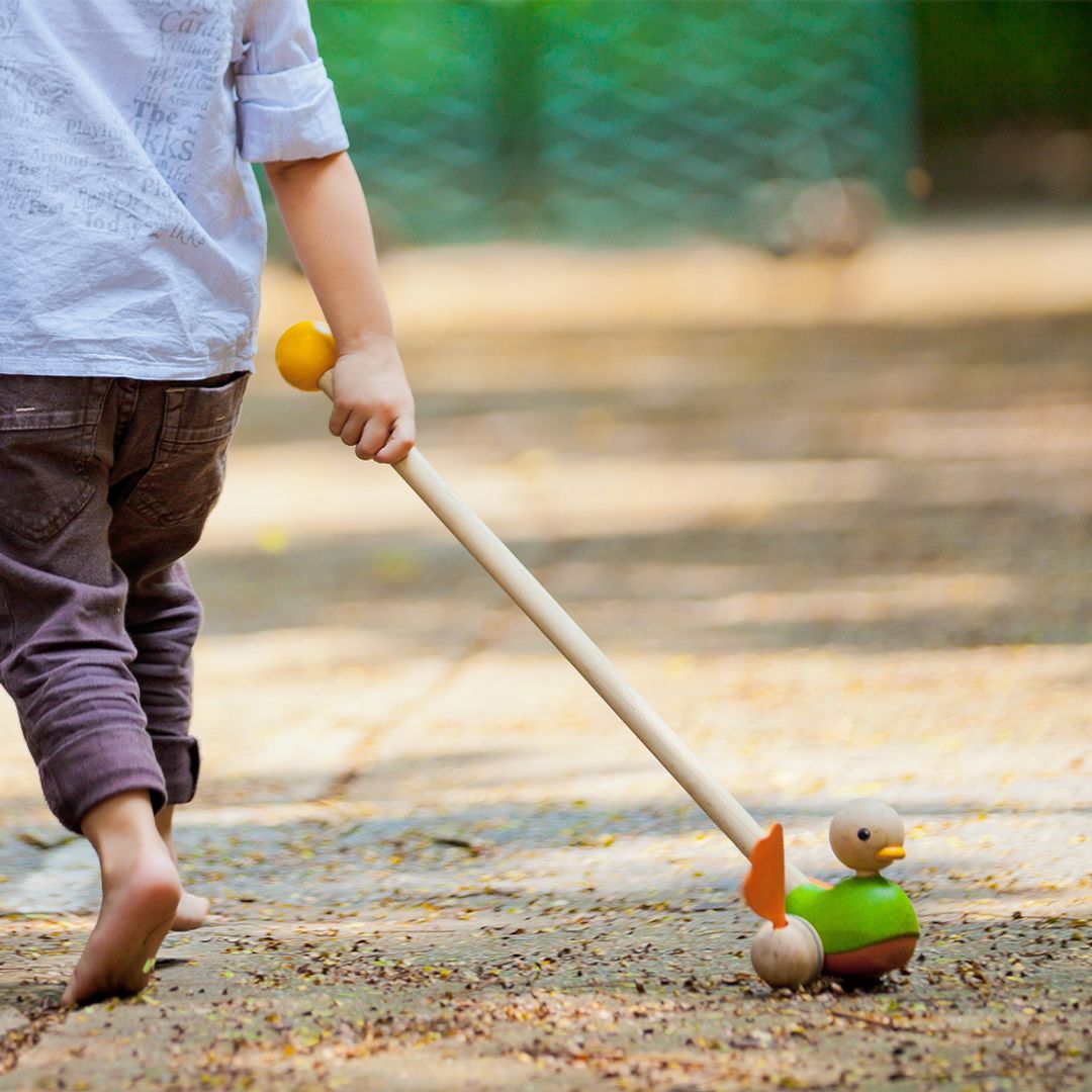 Child playing with a toy on a path outdoors