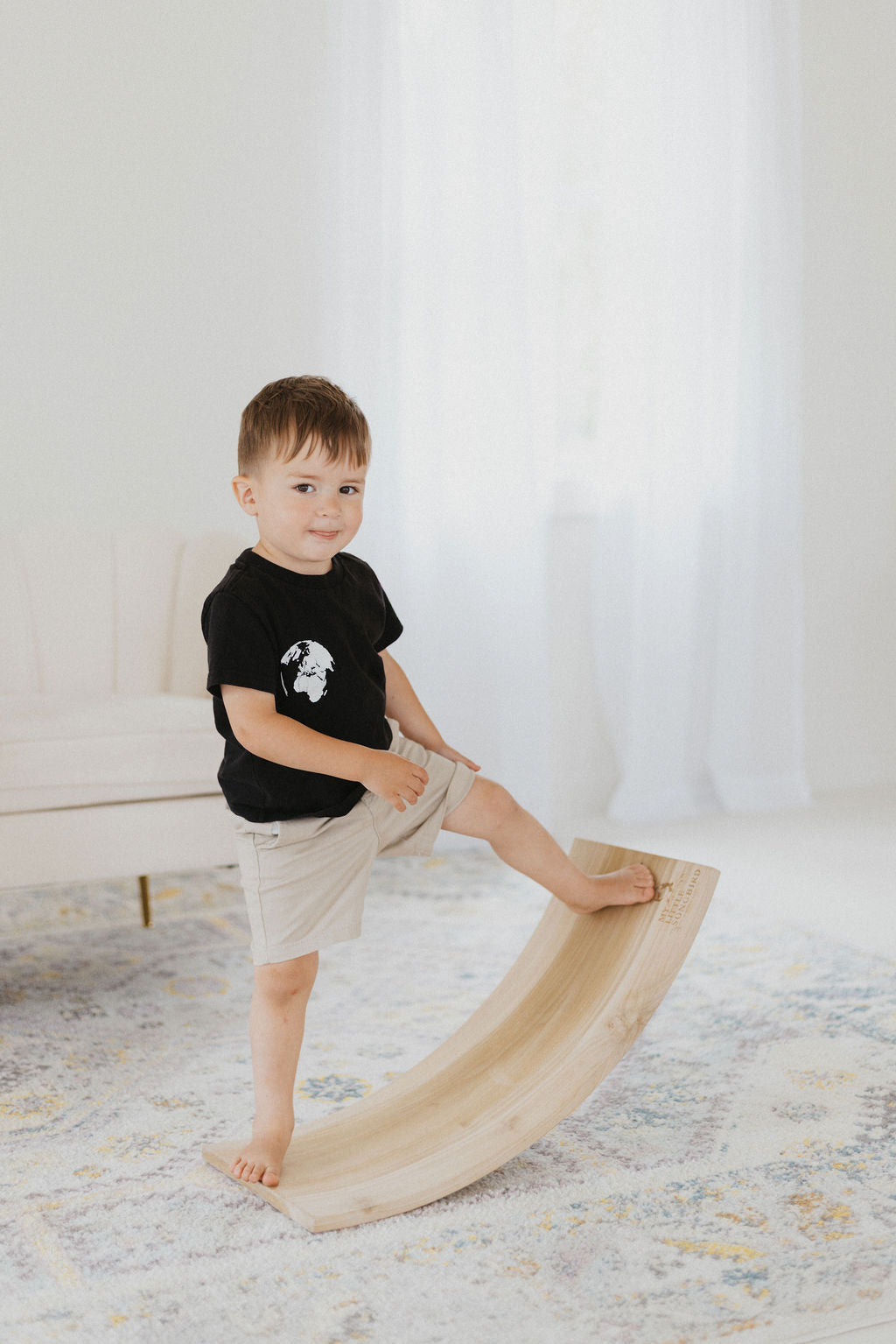 Child playing with a wooden toy on a light-colored floor.