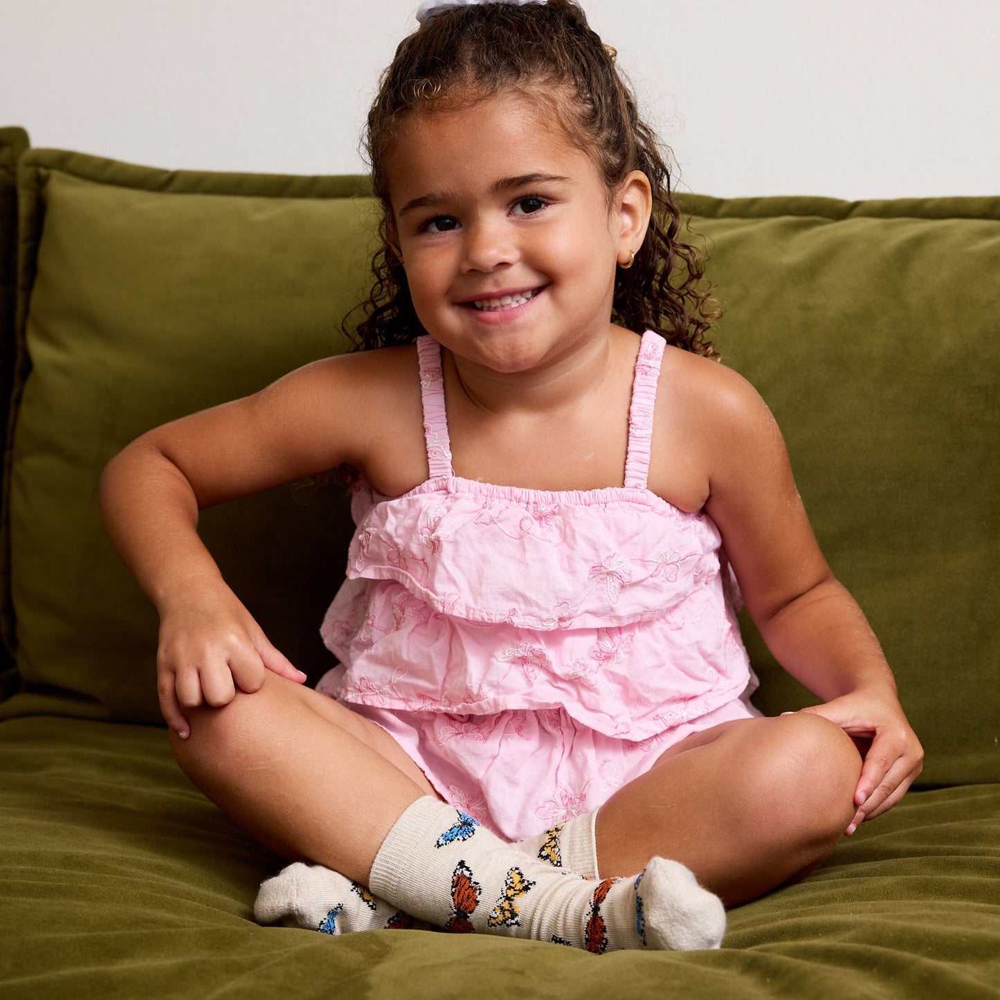 Young girl in a pink dress sitting on a green couch
