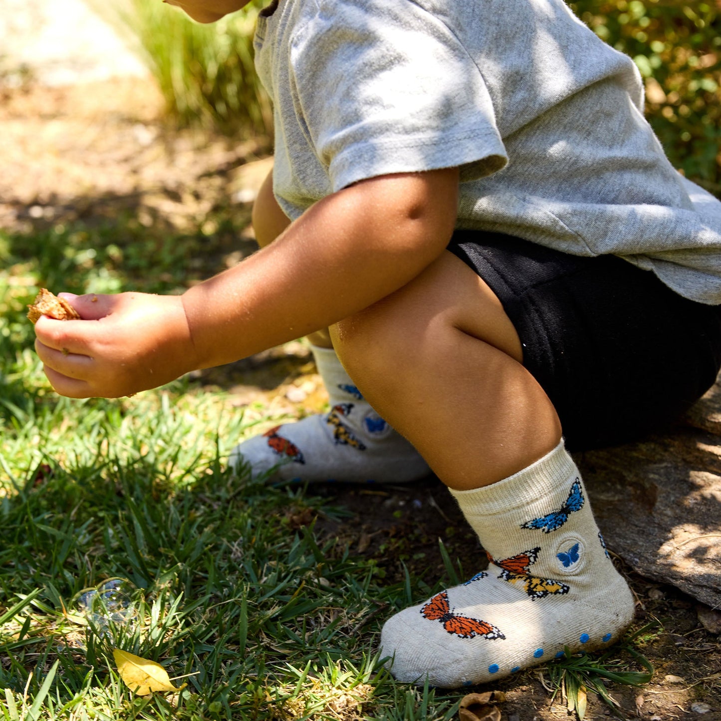 Child wearing socks with butterfly designs sitting on grass