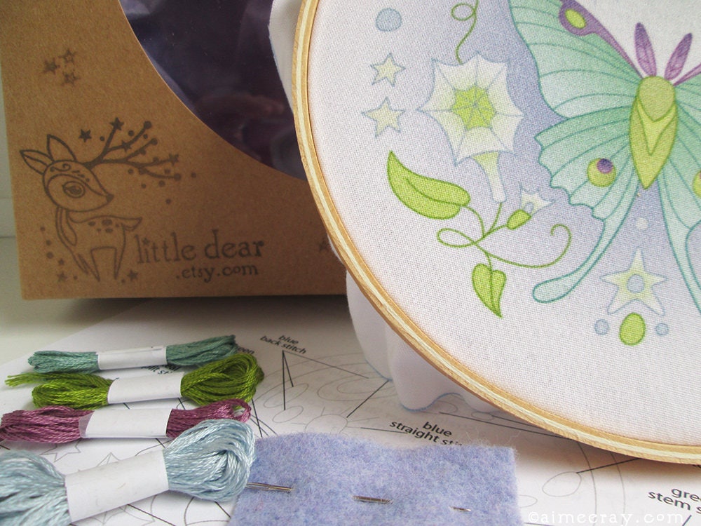 Embroidery hoop with butterfly design, threads, and 'little dear' packaging.