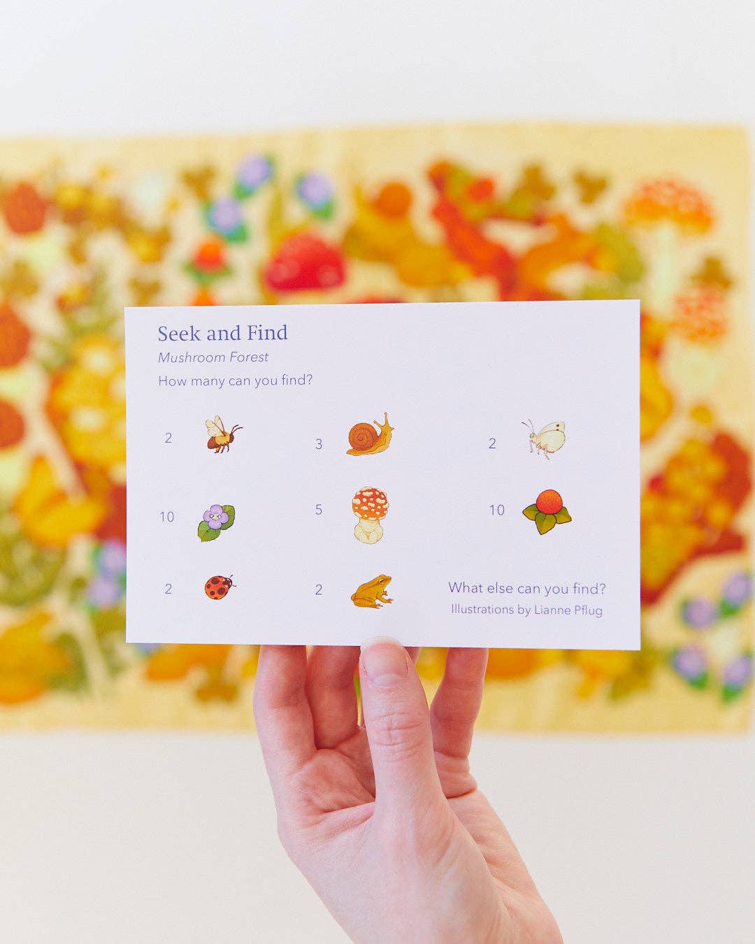 Hand holding a card with 'Seek and Find' game against a blurred colorful background
