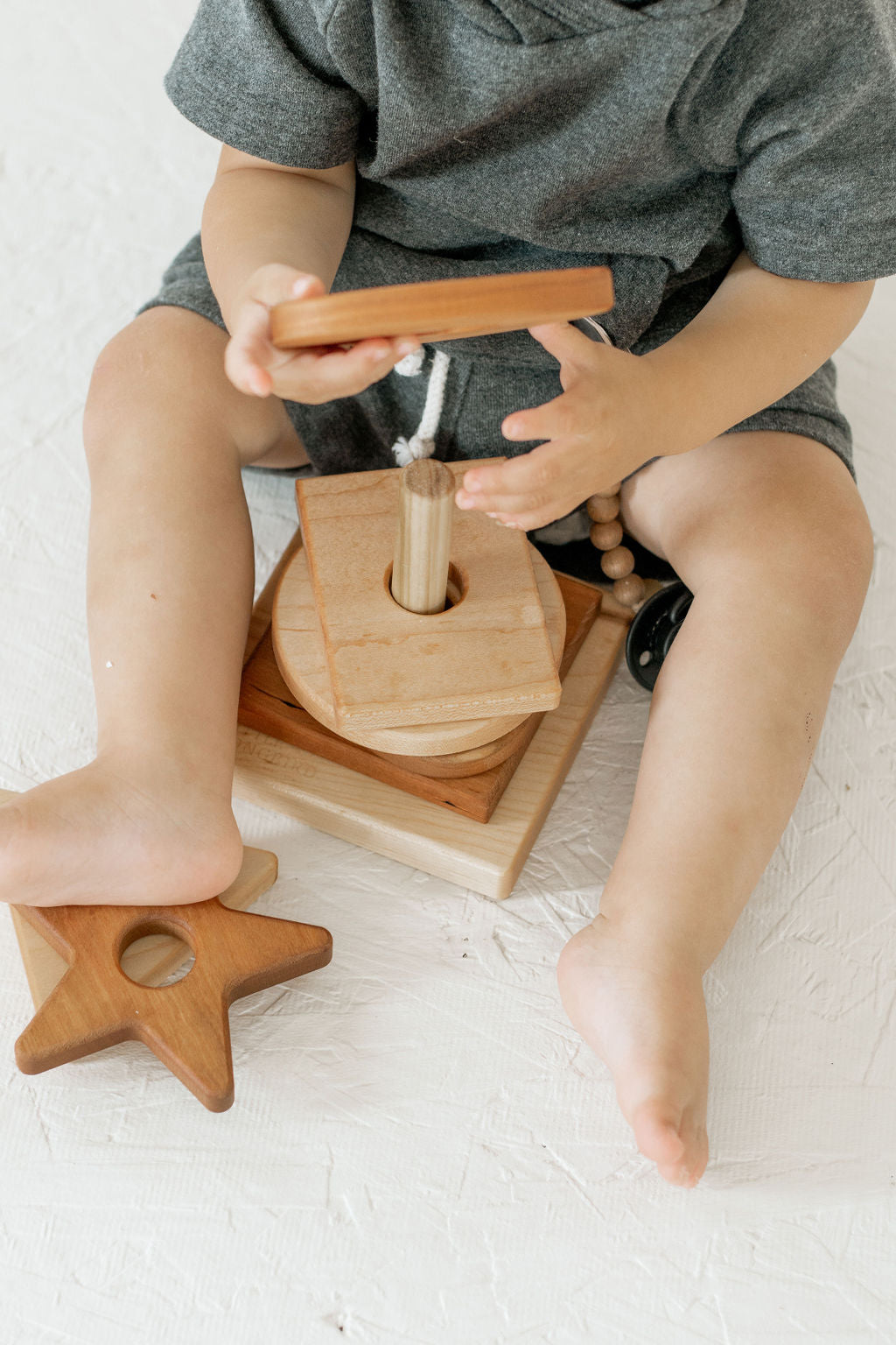 Child playing with a wooden toy on a light surface