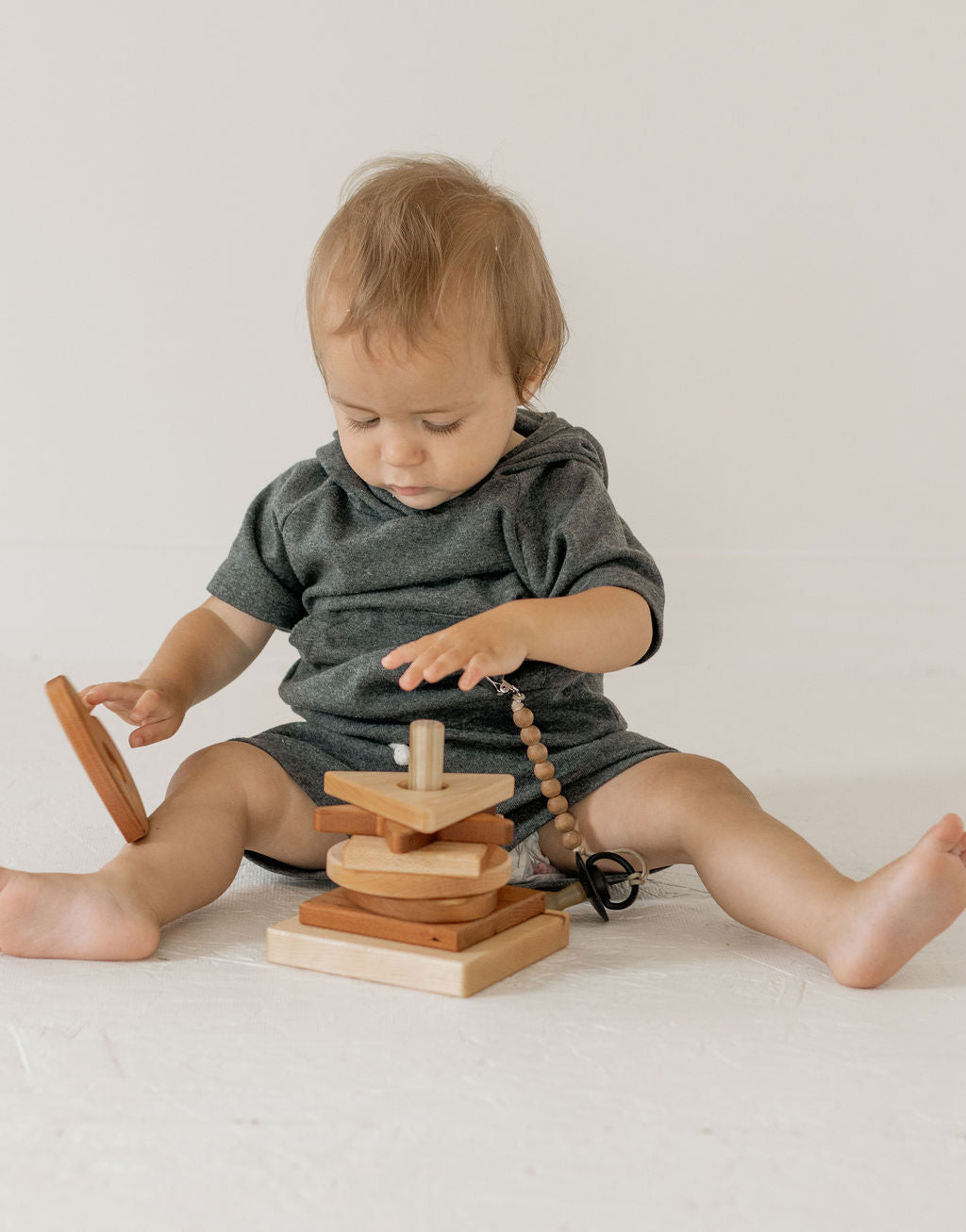 Child playing with wooden stacking blocks on a light background