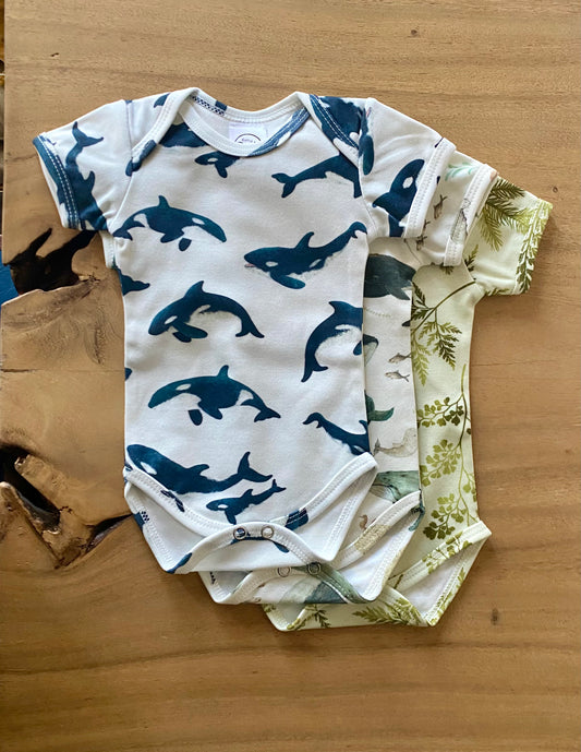 Baby onesie with green leaf pattern on a wooden surface