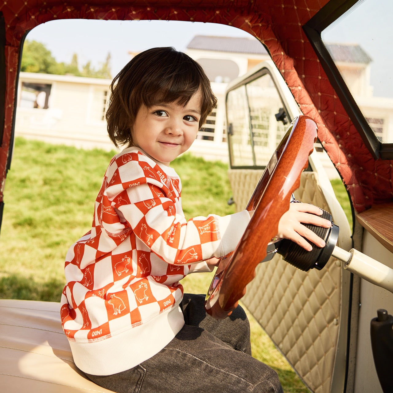 Child playing with a wooden steering wheel inside a vehicle