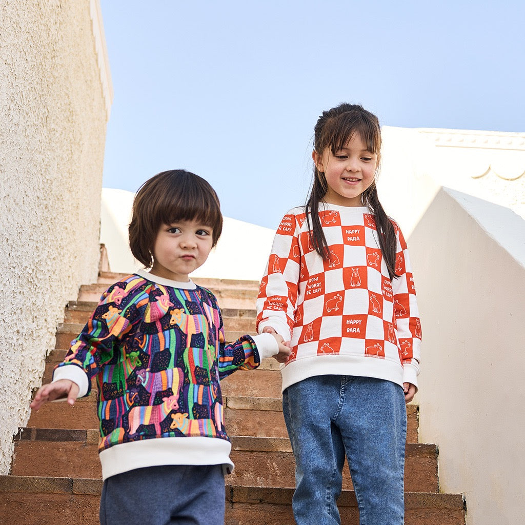 Two children standing on a set of stairs wearing colorful sweaters.