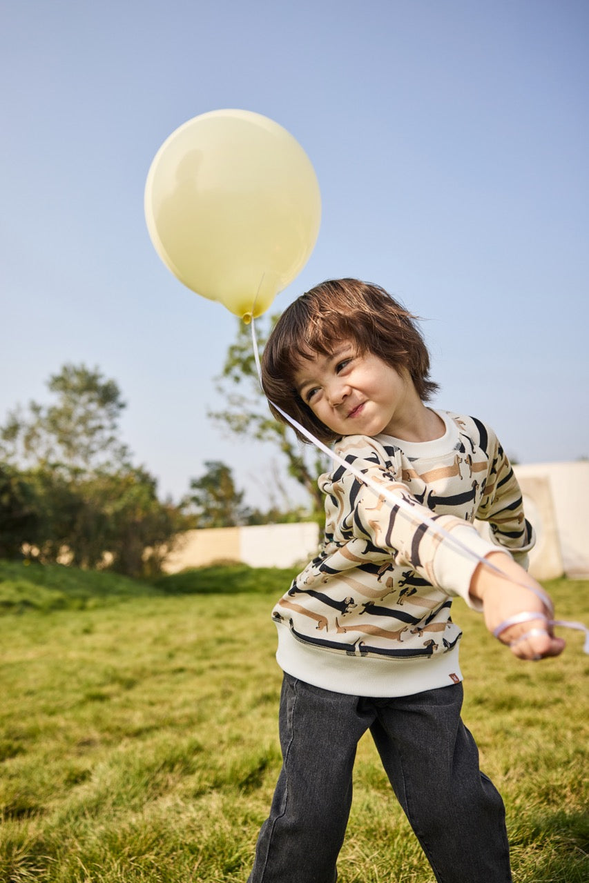 Child holding a yellow balloon outdoors on a clear day