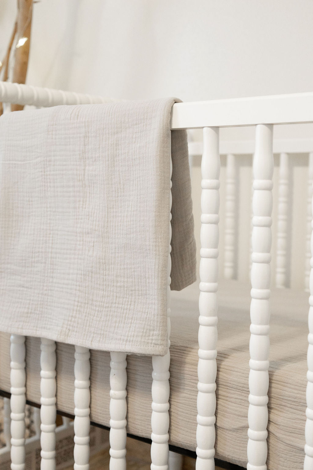 White crib with a textured gray blanket draped over the side