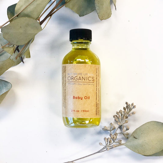 Bottle of baby oil with a label on a light background with eucalyptus leaves.
