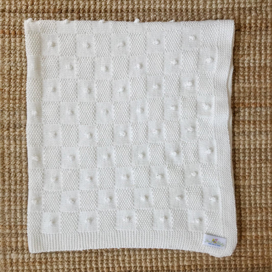 White textured blanket on a brown woven surface
