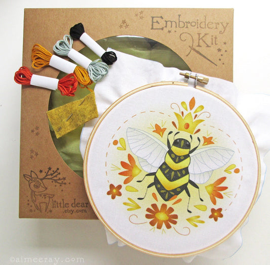Embroidery kit with a bee design and colorful thread skeins on a white background