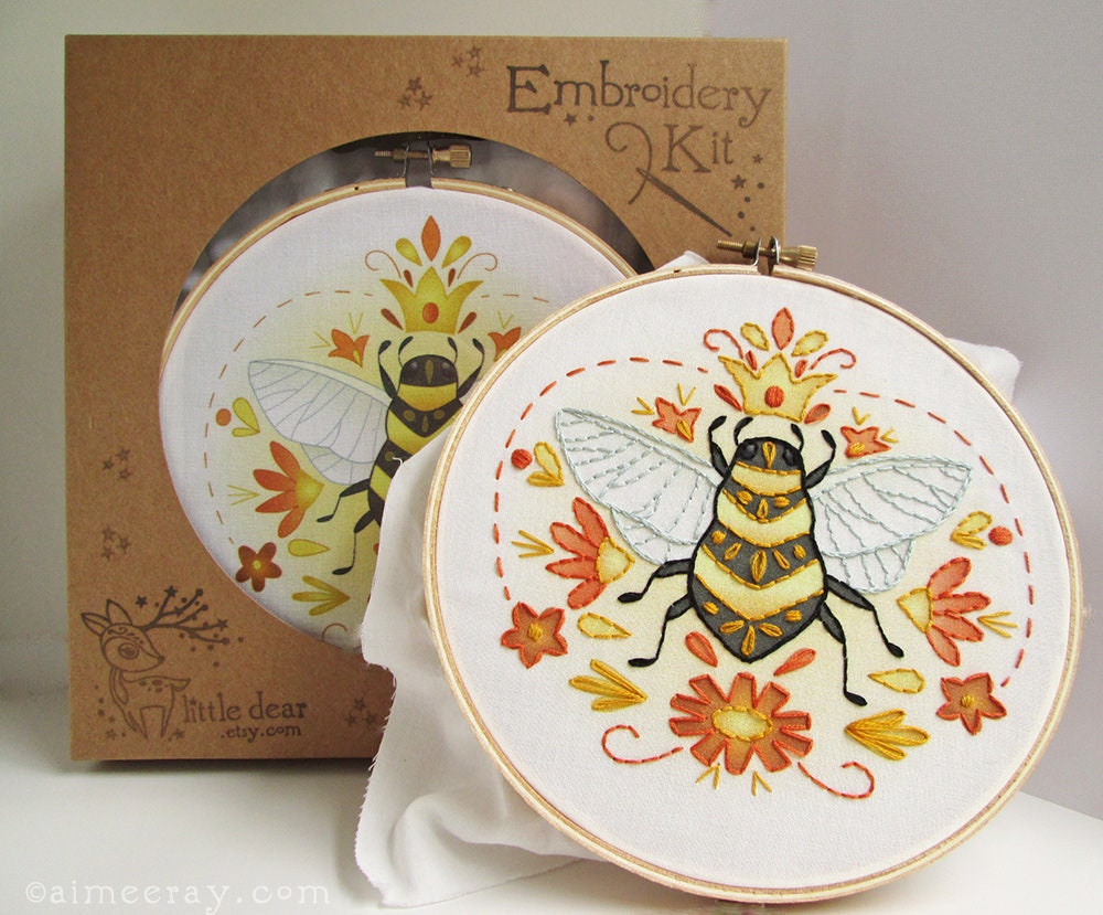Embroidery hoop with bee design and matching box labeled 'Embroidery Kit' on a white background.