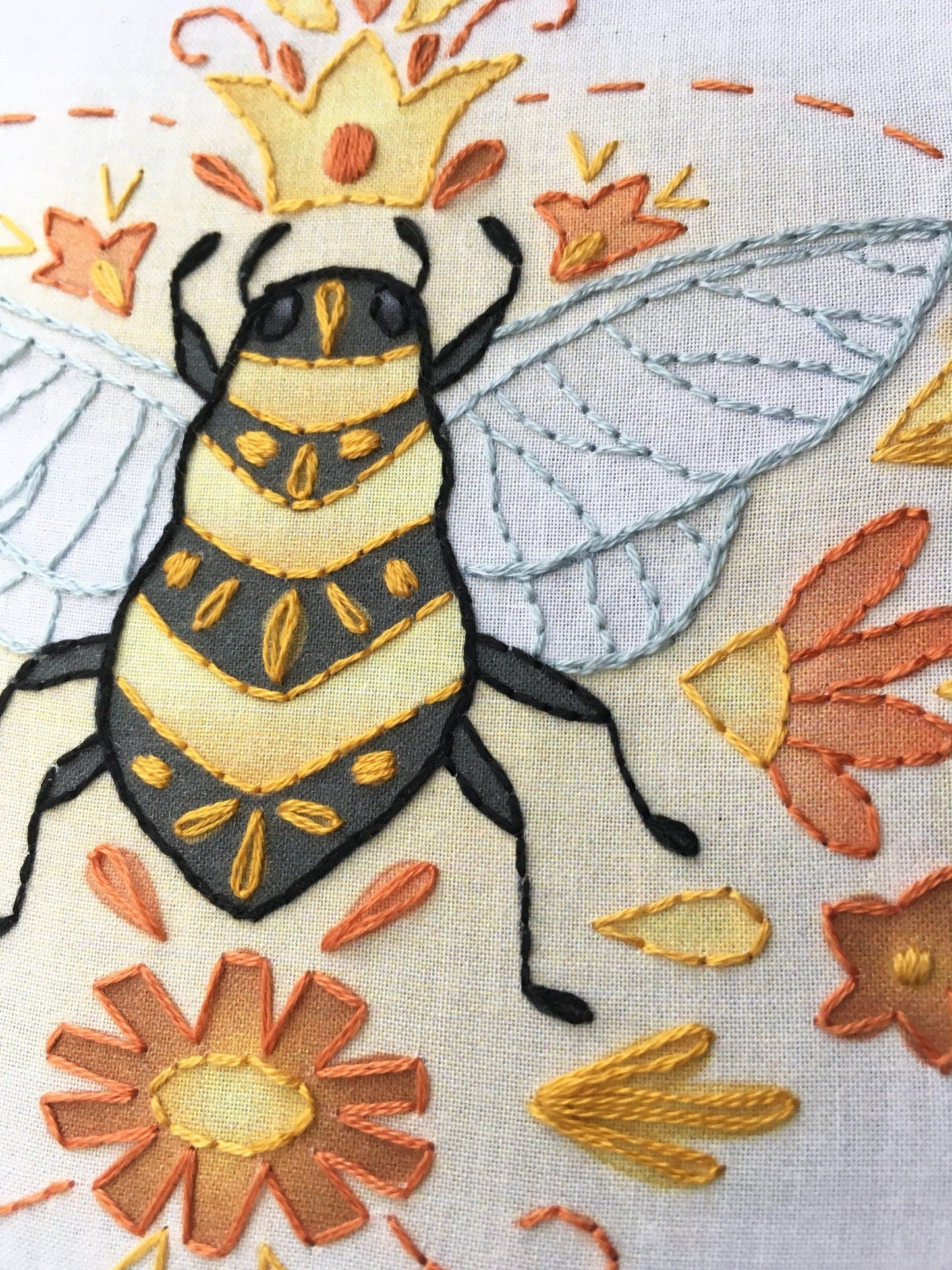 Embroidered bee design with flowers on a fabric background