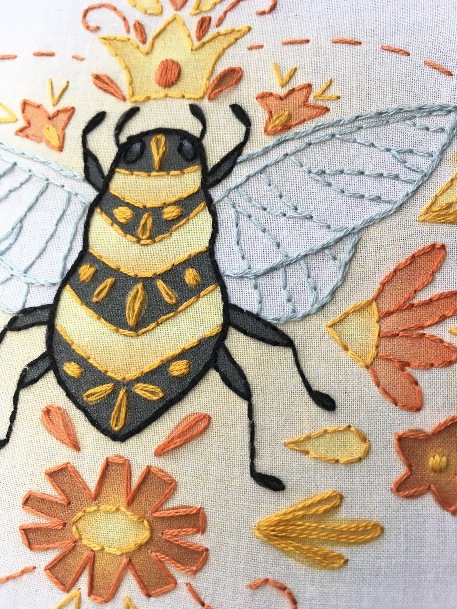 Embroidered bee design with flowers on a fabric background