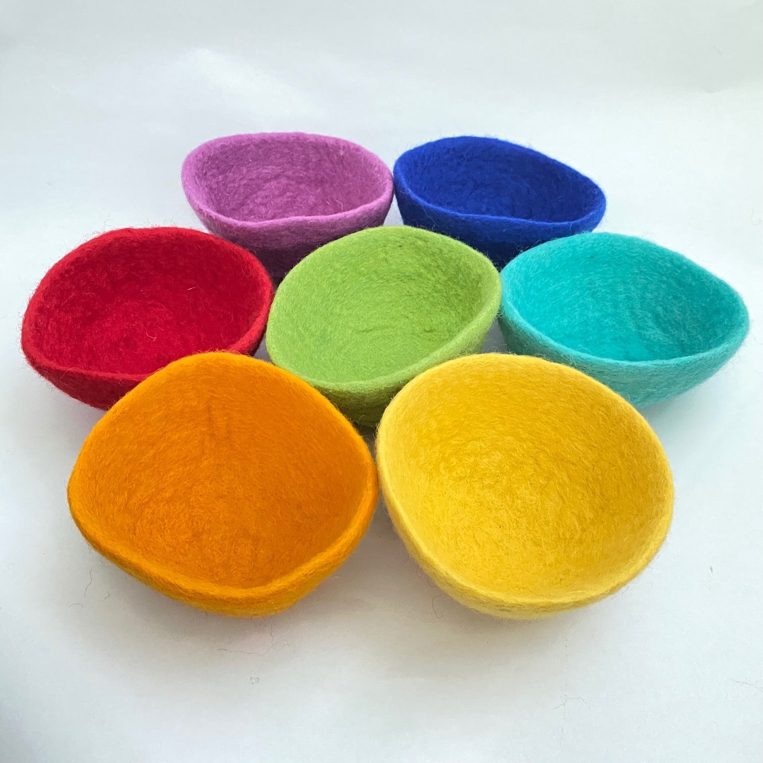 Set of colorful felt bowls on a white background