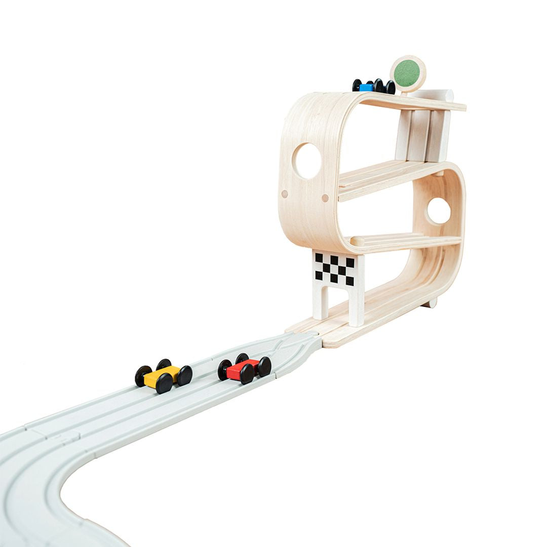 Wooden toy race track with cars on a white background